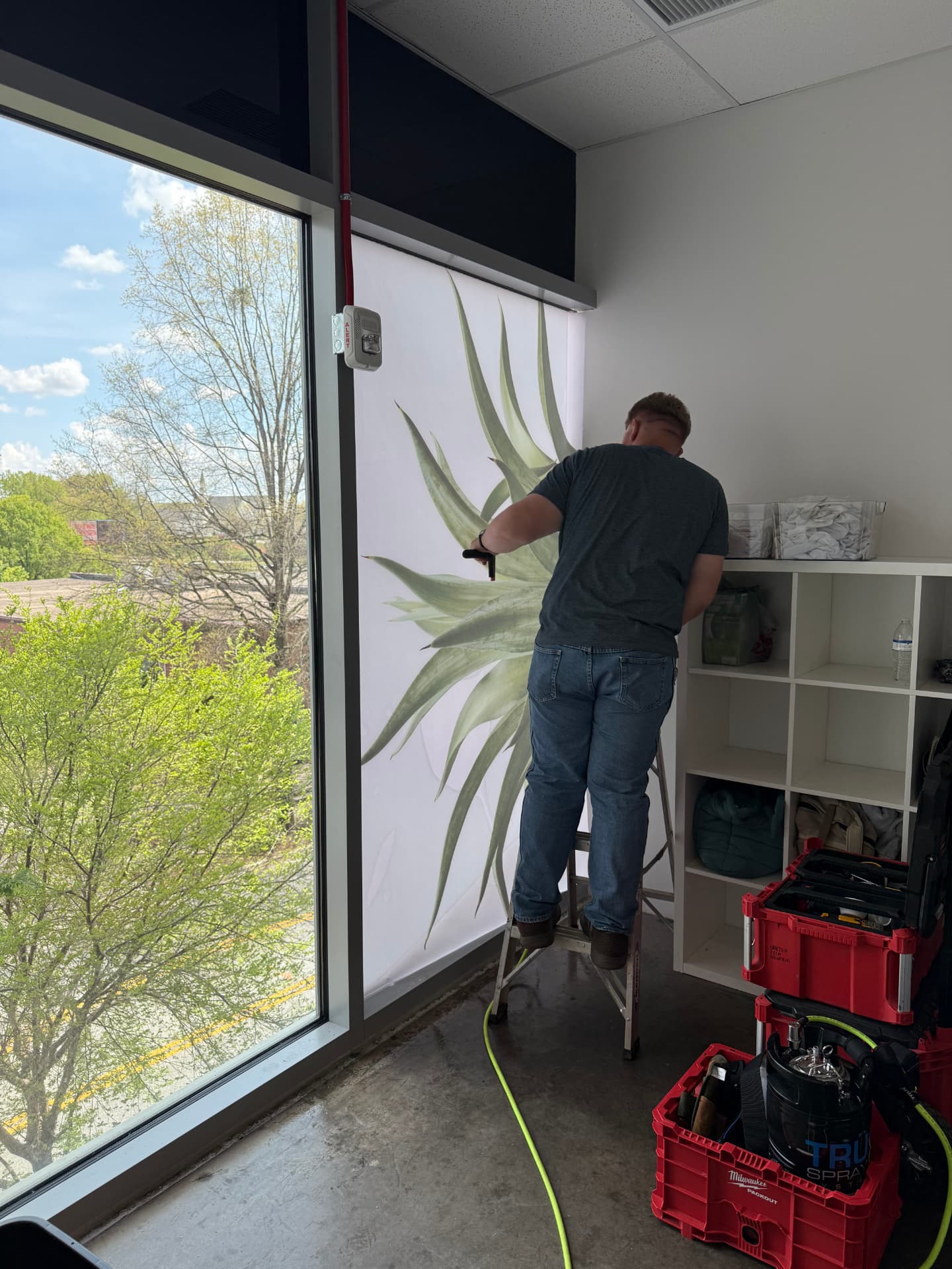 Installer applying a decorative graphic film to interior office glass