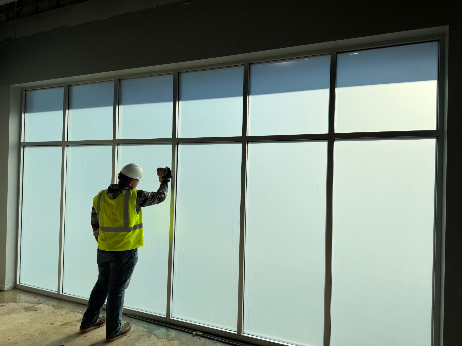 Installer finishing frosted privacy film on a commercial glass wall