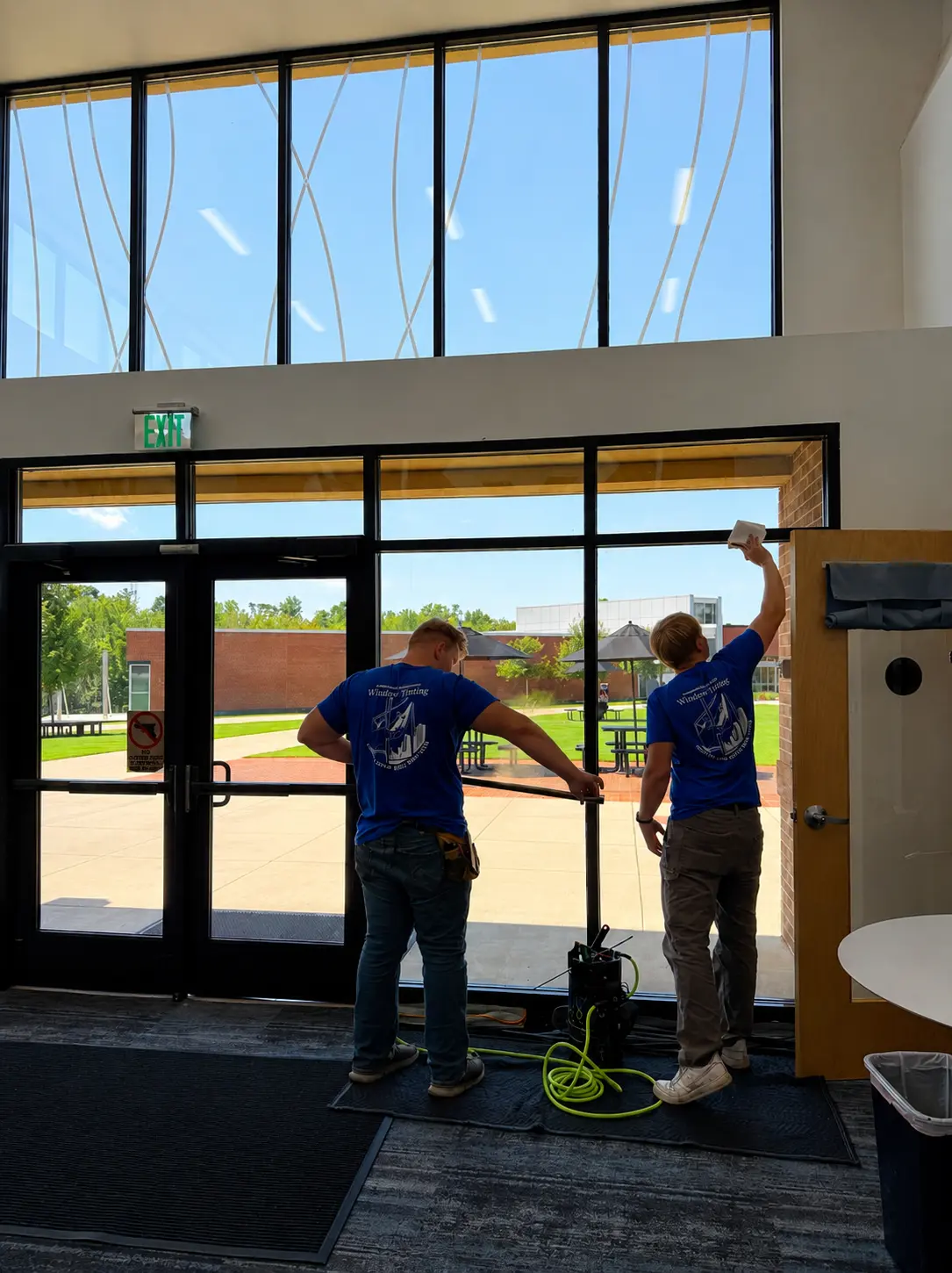Installers working on glass entry doors at a school